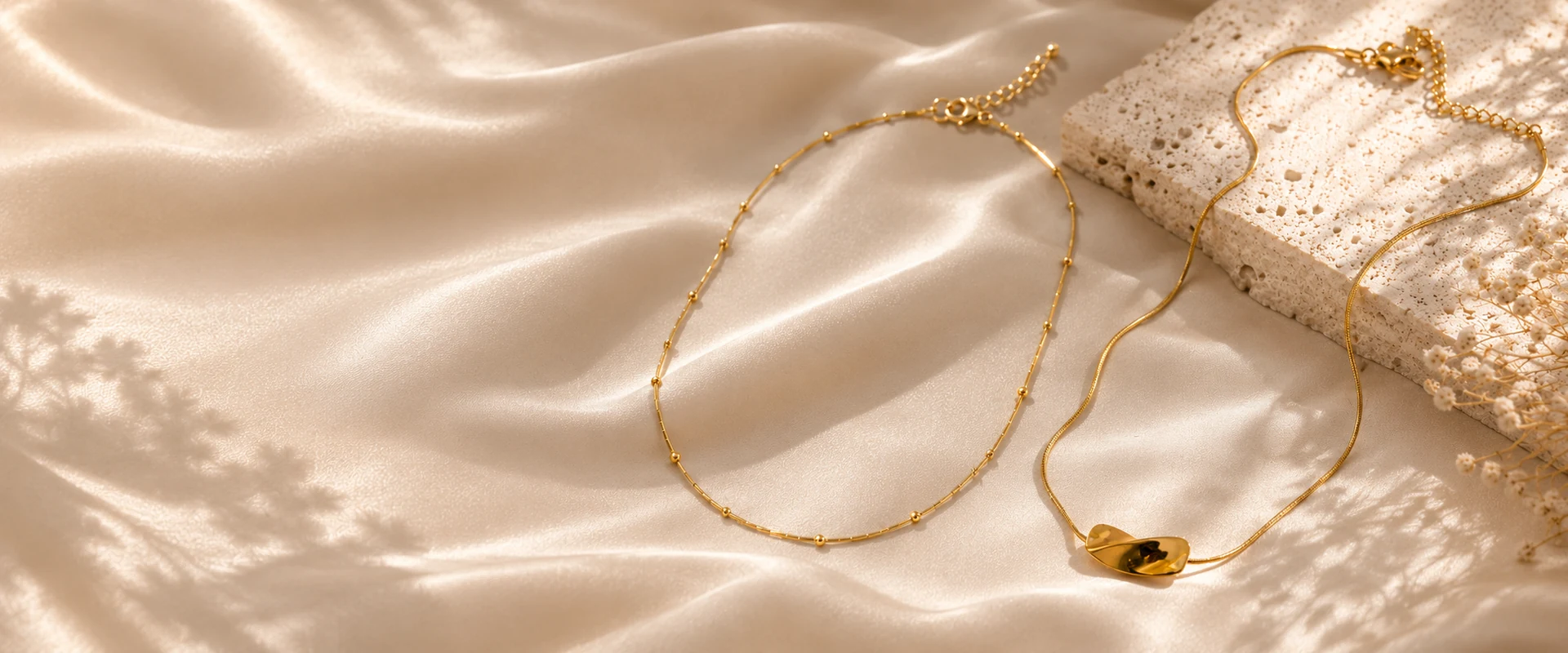 Deux colliers dorés sur du satin beige et de la pierre claire